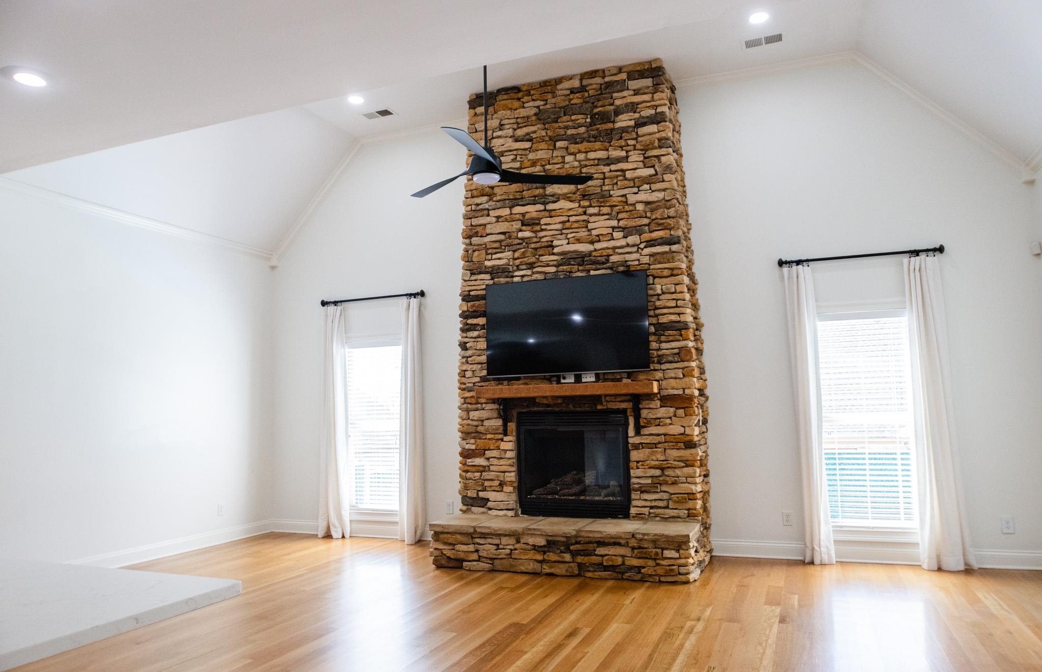 5309 Evergreen Road Lakeland, TN 38002 - Photo 8 of 40 Unfurnished living room featuring visible vents, a stone fireplace, a ceiling fan, and wood finished floors
