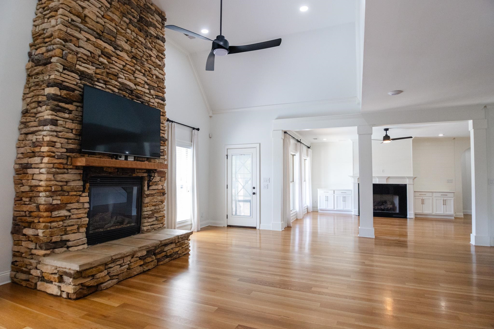 5309 Evergreen Road Lakeland, TN 38002 - Photo 9 of 40 Unfurnished living room featuring light wood-style floors, a stone fireplace, and ceiling fan