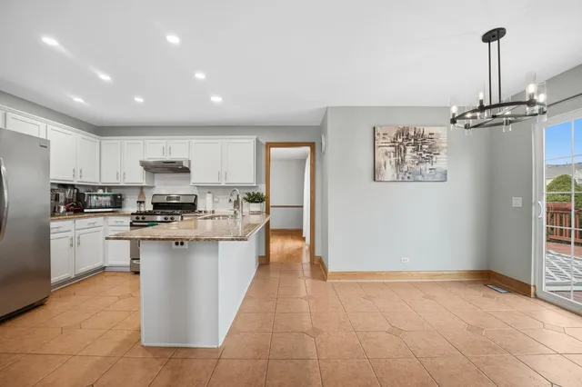 a kitchen with stainless steel appliances granite countertop a refrigerator a sink dishwasher a stove and white cabinets with wooden floor