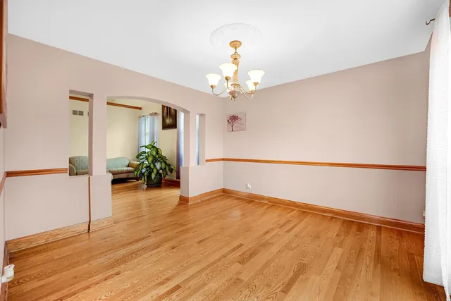 a view of an empty room with wooden floor and a potted plant