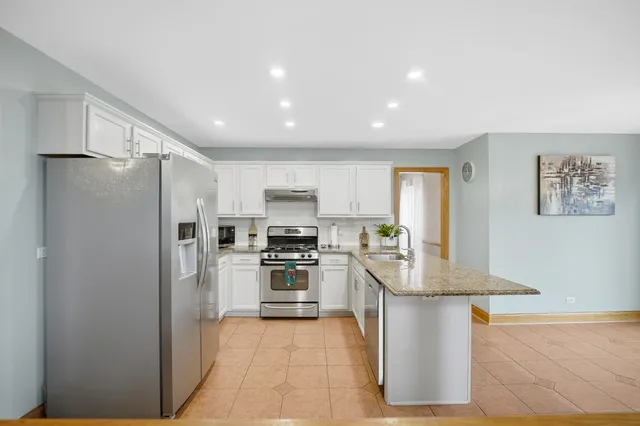 a kitchen with stainless steel appliances granite countertop a refrigerator a stove top oven a sink and dishwasher