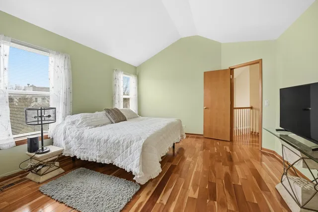 a bedroom with a bed flat screen tv and windows