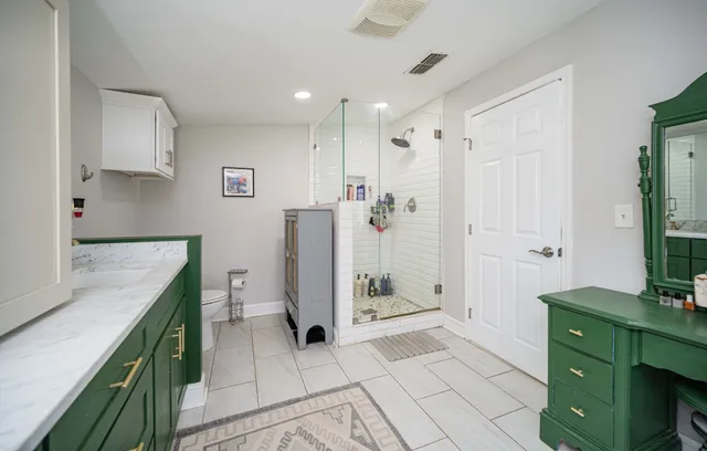 a bathroom with a granite countertop sink a mirror and shower