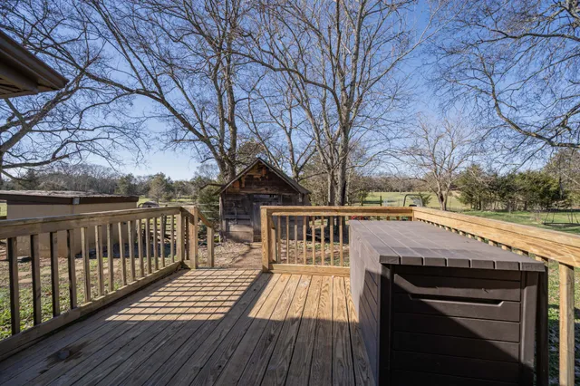 a view of house with wooden deck and trees