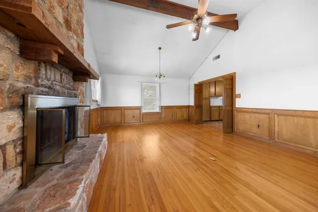 a view of empty room with wooden floor and fireplace