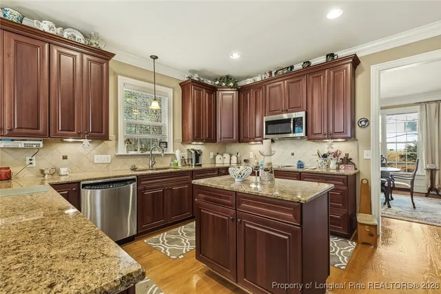 a kitchen with kitchen island granite countertop a sink stove and cabinets