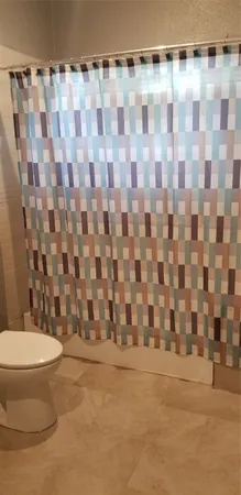 a bathroom with a toilet and a shower curtain