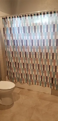 a bathroom with a toilet and a shower curtain