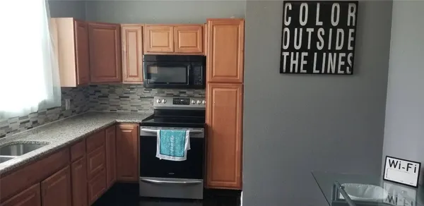 a kitchen with stainless steel appliances granite countertop a stove a sink and a microwave