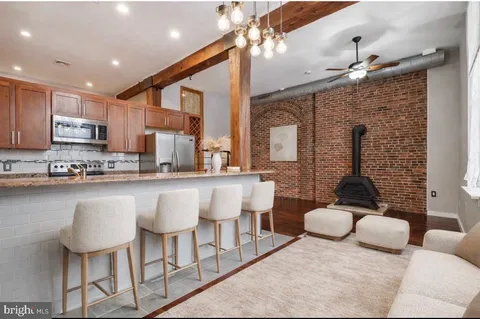 a kitchen with stainless steel appliances granite countertop a sink a stove a refrigerator cabinets and chairs