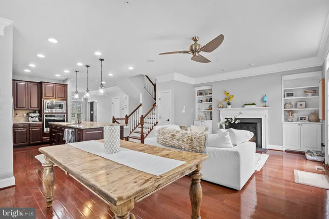 a living room with furniture kitchen view and a wooden floor