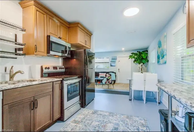 a kitchen with stainless steel appliances granite countertop a sink a stove a refrigerator cabinets and living room view