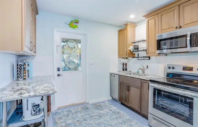 a kitchen with kitchen island granite countertop a stove top oven a sink a counter space and cabinets
