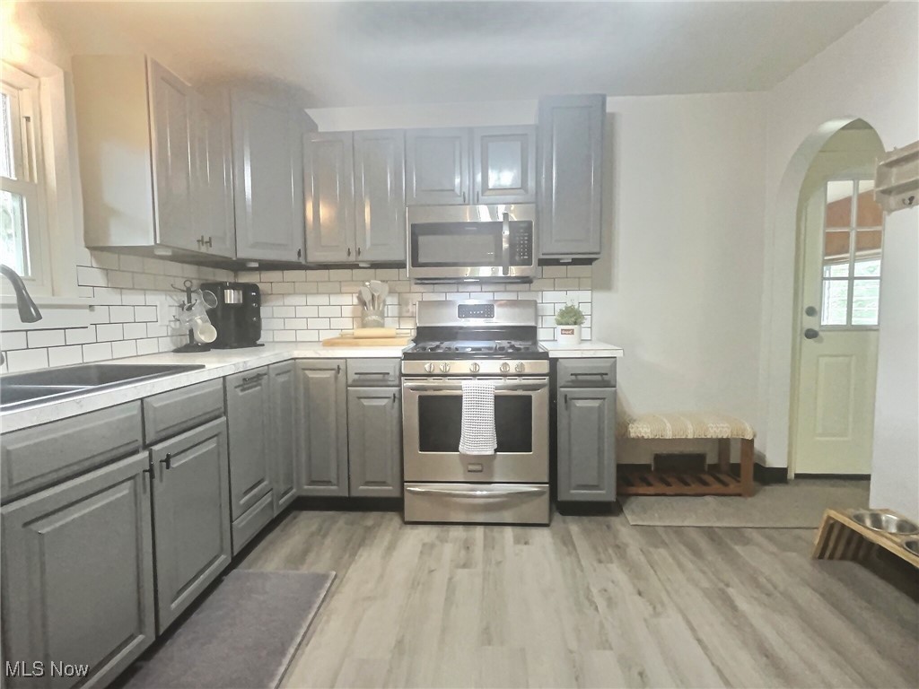 3688 Easton Road Norton, OH 44203 - Photo 16 of 37 Kitchen featuring stainless steel appliances, decorative backsplash, light wood-type flooring, sink, and gray cabinetry