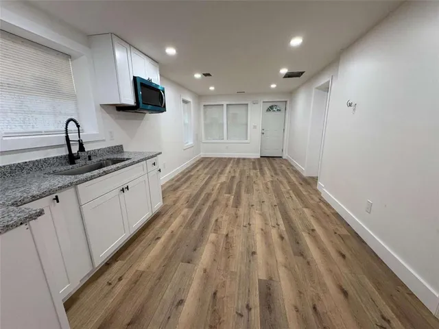 a view of kitchen with stainless steel appliances wooden floor large window and wooden floor