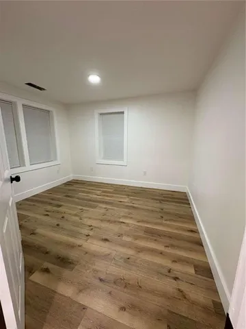 an empty room with wooden floor and fan