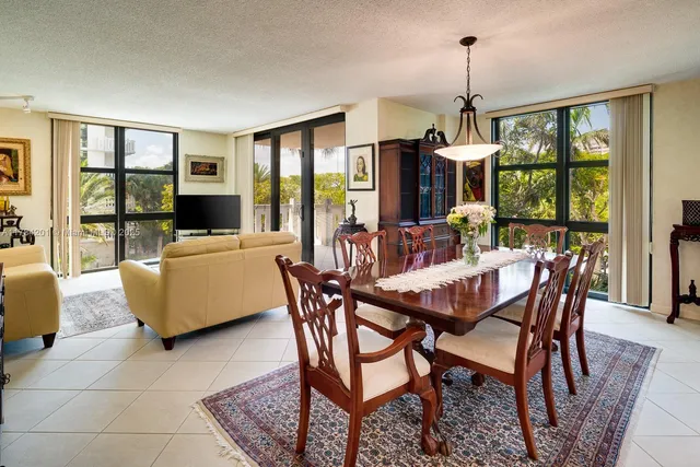 a dining room with furniture large windows and a chandelier