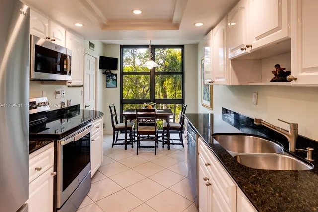 a kitchen with kitchen island granite countertop a sink appliances and cabinets