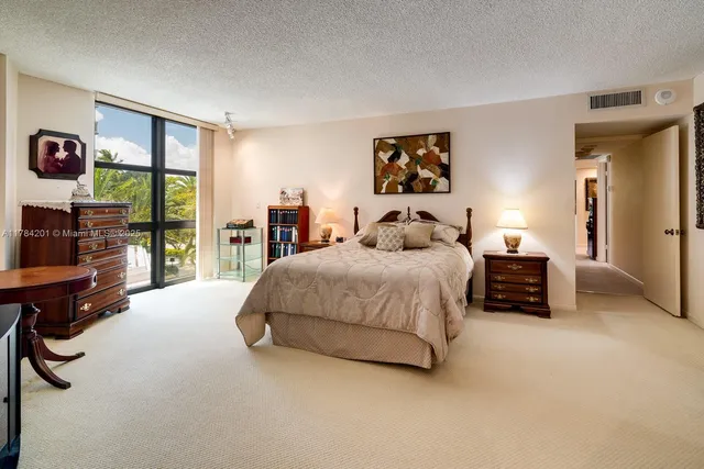 a spacious bedroom with a bed a couch and large window