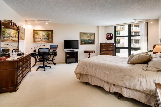a spacious bedroom with a bed a table and a flat screen television