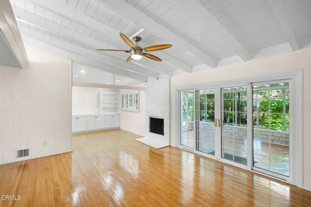 a view of a livingroom with a fireplace a ceiling fan and wooden floor