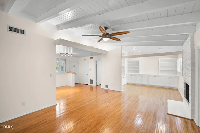 a view of empty room with wooden floor and fan
