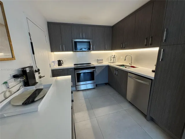 a kitchen with stainless steel appliances a sink dishwasher stove refrigerator and cabinets