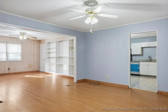 an empty room with wooden floor chandelier and windows