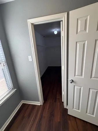 an empty room with wooden floor chandelier and windows