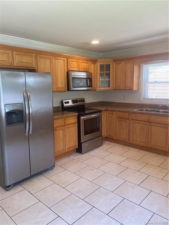 7323 Idlewild Road Charlotte, NC 28212 - Photo 3 of 13 a kitchen with stainless steel appliances granite countertop a refrigerator and a sink