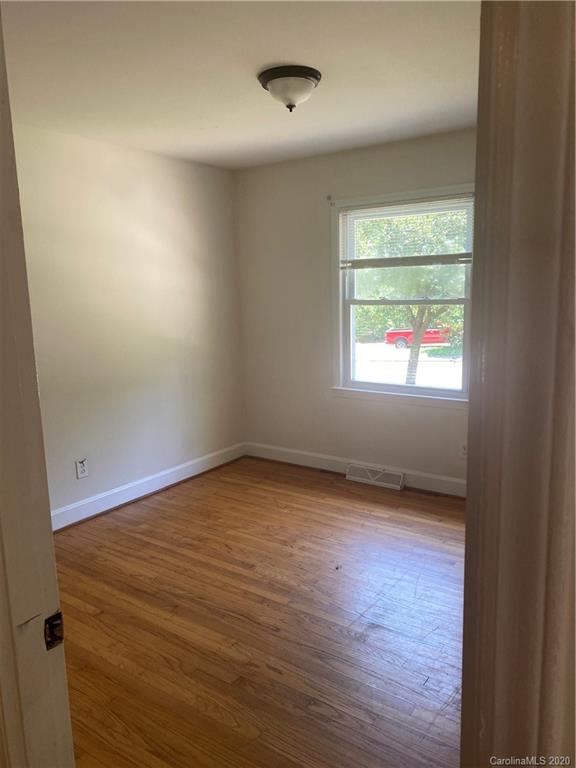 7323 Idlewild Road Charlotte, NC 28212 - Photo 8 of 13 an empty room with wooden floor and windows
