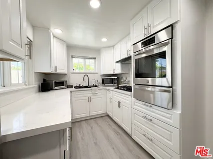 a kitchen with granite countertop white cabinets and stainless steel appliances