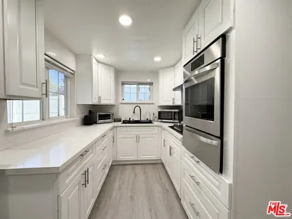 a kitchen with granite countertop a refrigerator and white cabinets
