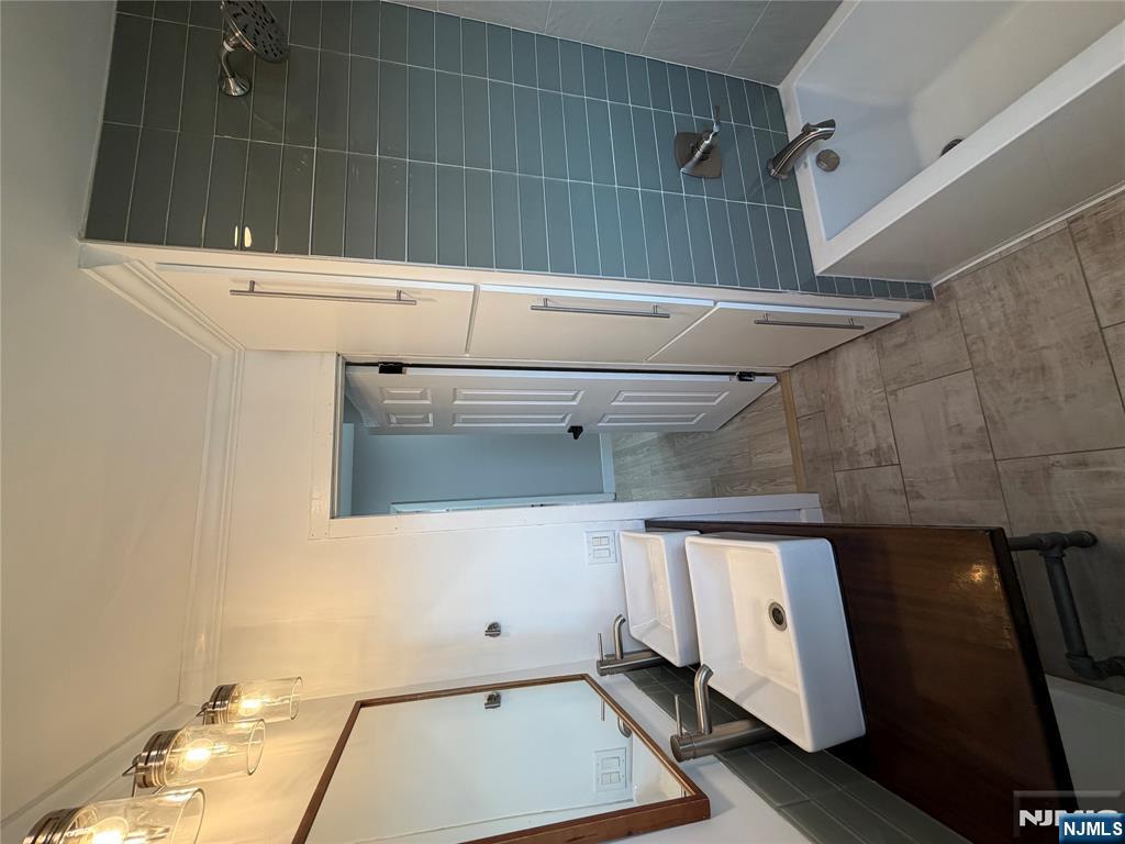 157 Cottage Place, Unit 2 Fairview, NJ 07022 - Photo 9 of 33 a bathroom with a tub a sink and a large mirror