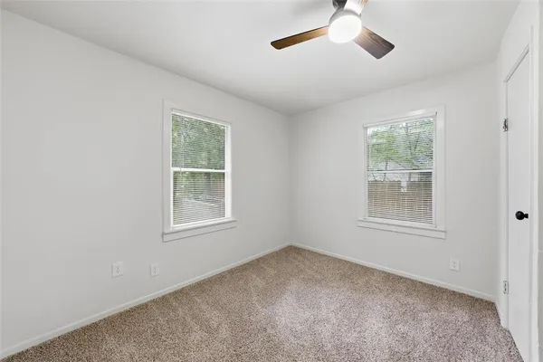 an empty room with a window and a fan