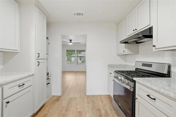 a kitchen with white cabinets and appliances