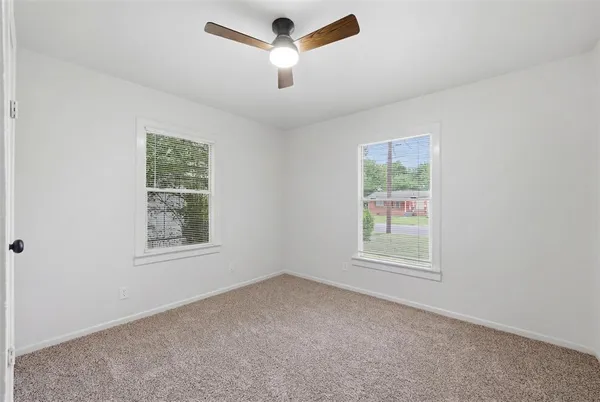an empty room with a window and a ceiling fan