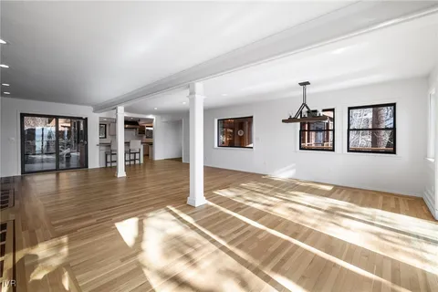 a view of a livingroom with wooden floor and kitchen view