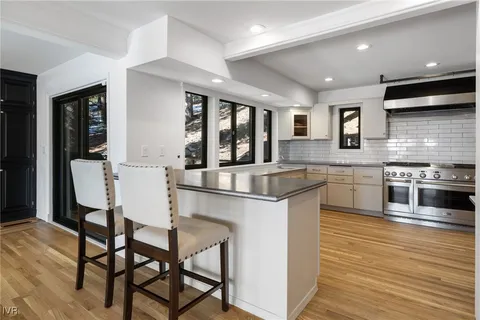 a kitchen with stainless steel appliances granite countertop a stove top oven a sink a dining table and chairs