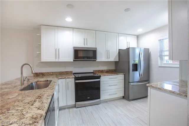 a kitchen with stainless steel appliances granite countertop a sink and a stove top oven with wooden floor