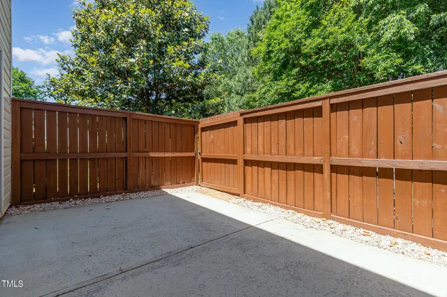 a view of a backyard with wooden fence and large trees