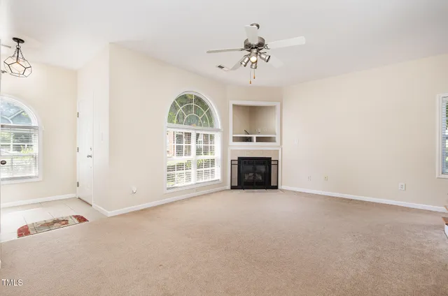 an empty room with windows chandelier and fireplace