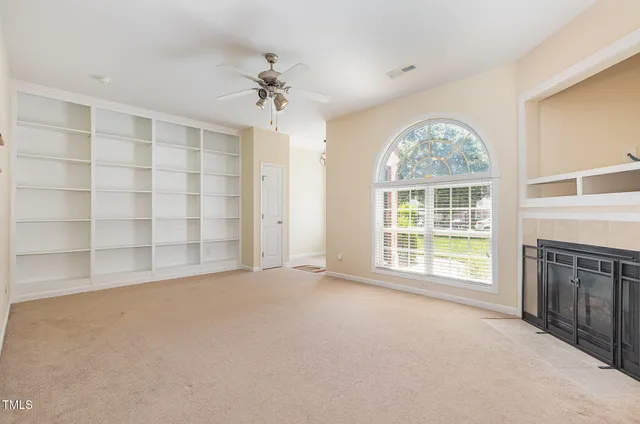 an empty room with windows chandelier fan and windows
