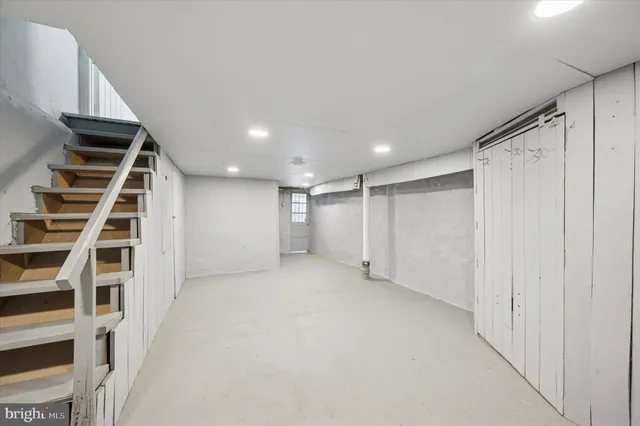 a view of an empty room with wooden floor and stairs