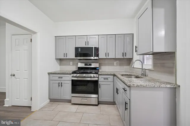 a kitchen with stainless steel appliances granite countertop a stove a sink and a microwave