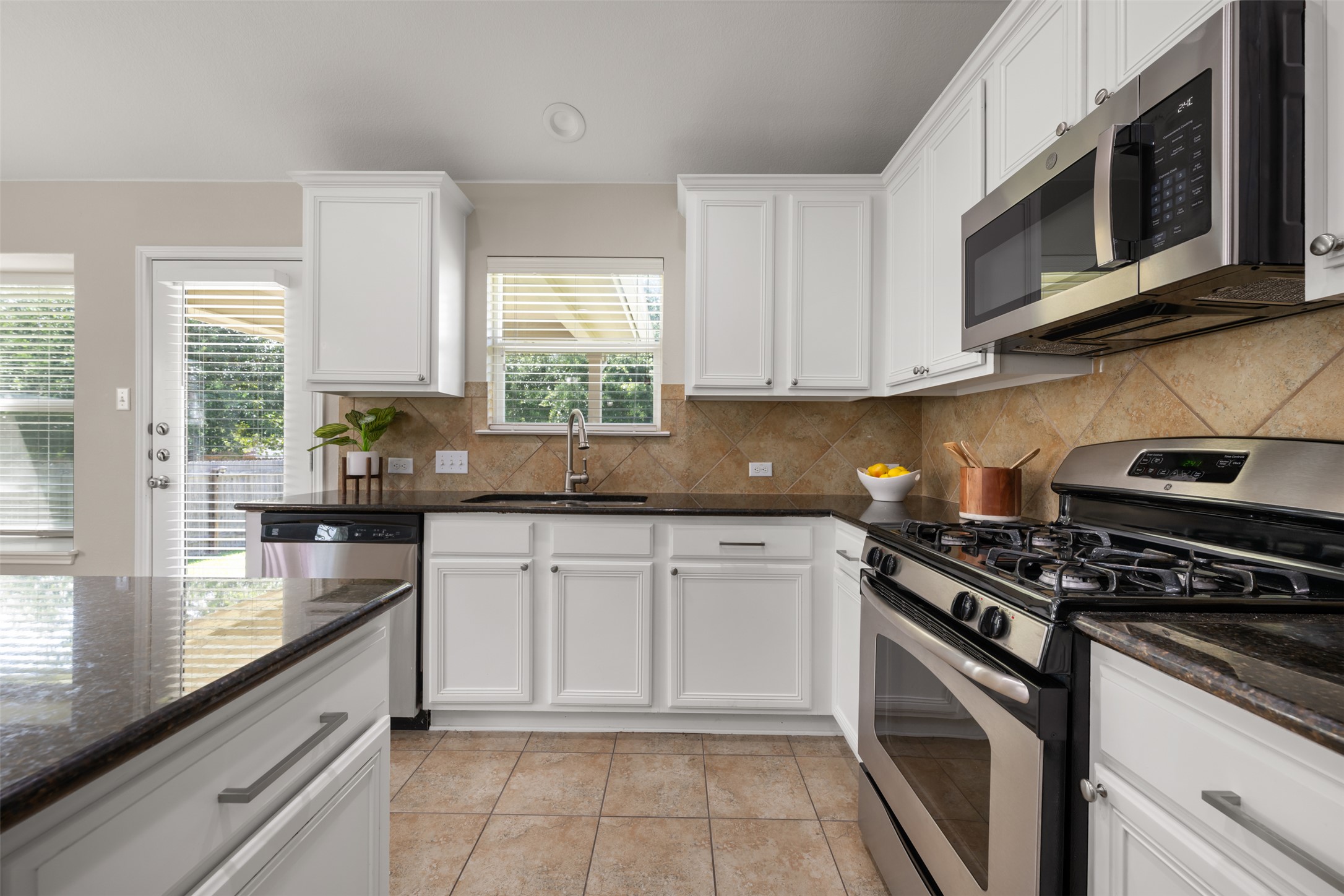 18820 Edinburgh Castle Road Pflugerville, TX 78660 - Photo 12 of 37 a kitchen with stainless steel appliances granite countertop white cabinets granite counter tops and a window