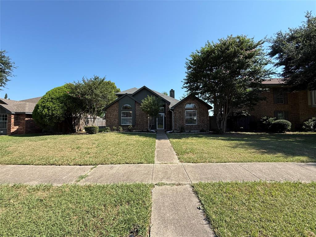7913 Rice Drive Rowlett, TX 75088 - Photo 2 of 25 Brick facade residence with a central walkway, arched windows, and mature trees