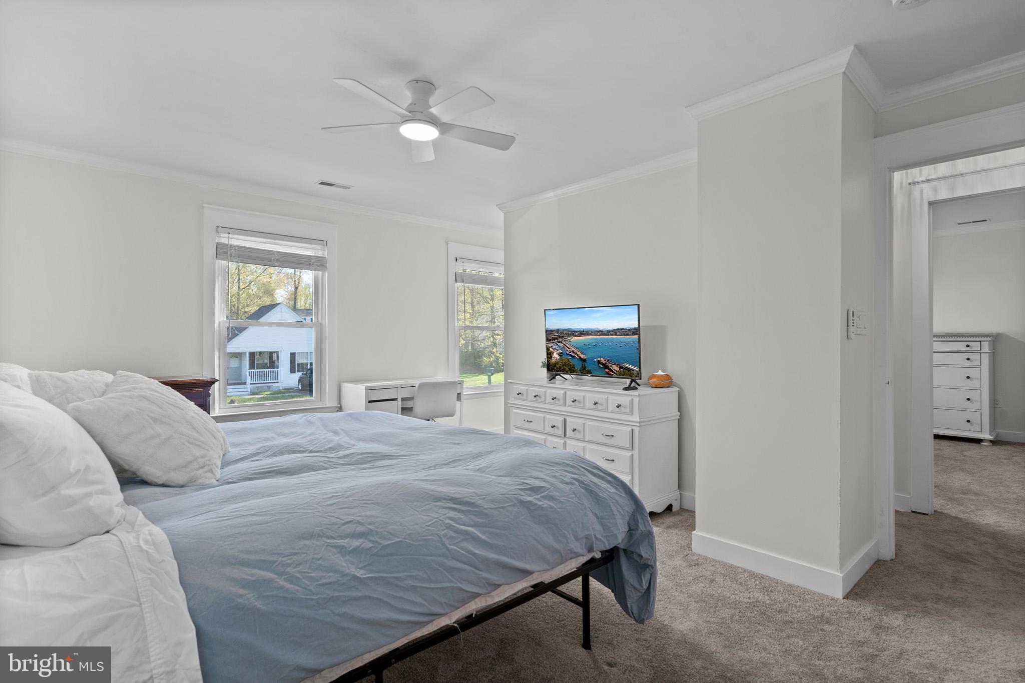 3704 9th Street North Beach, MD 20714 - Photo 19 of 42 a bedroom with a large bed a chandelier and flat screen tv