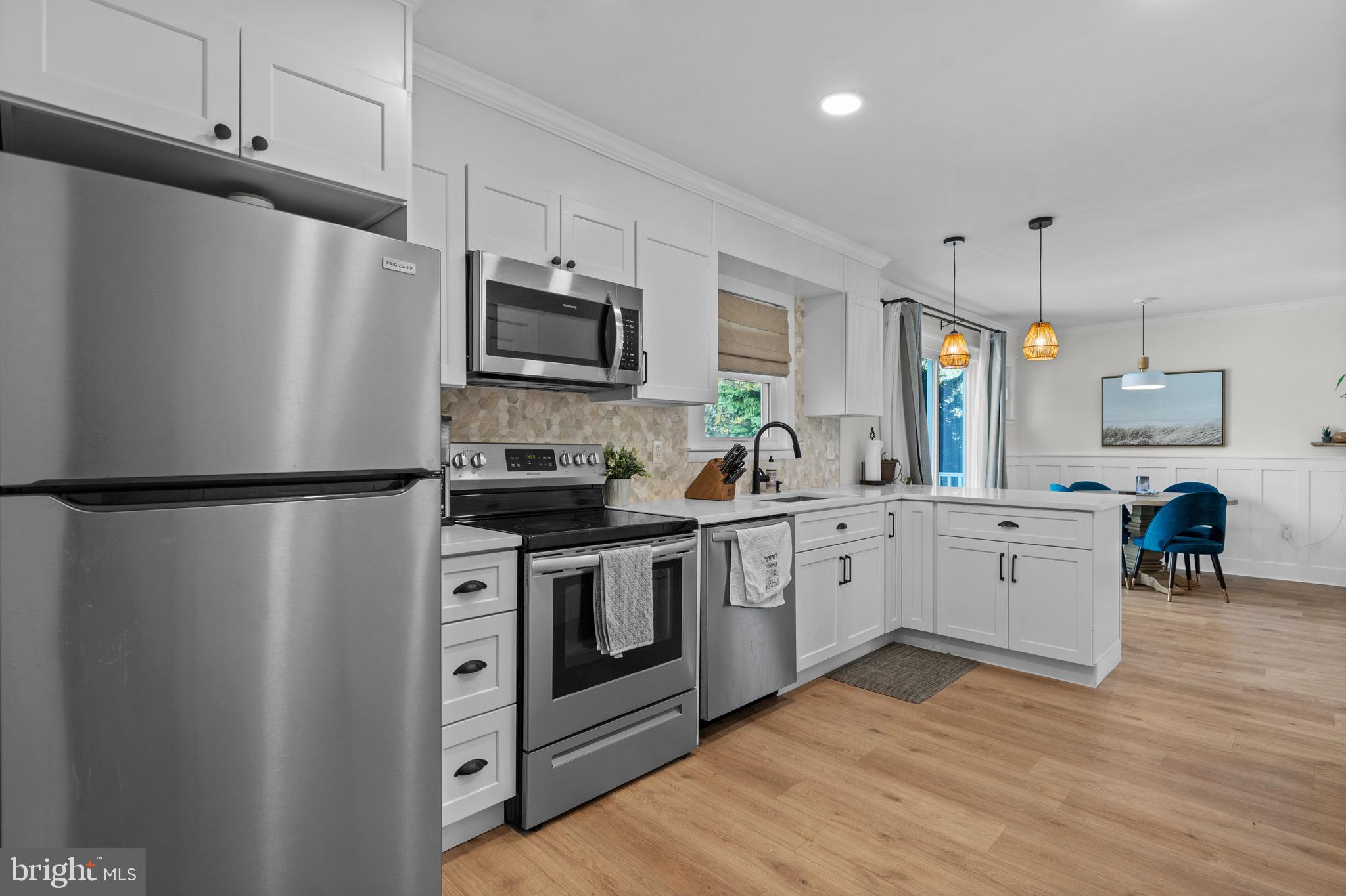 3704 9th Street North Beach, MD 20714 - Photo 6 of 42 a kitchen with white cabinets stainless steel appliances and a refrigerator