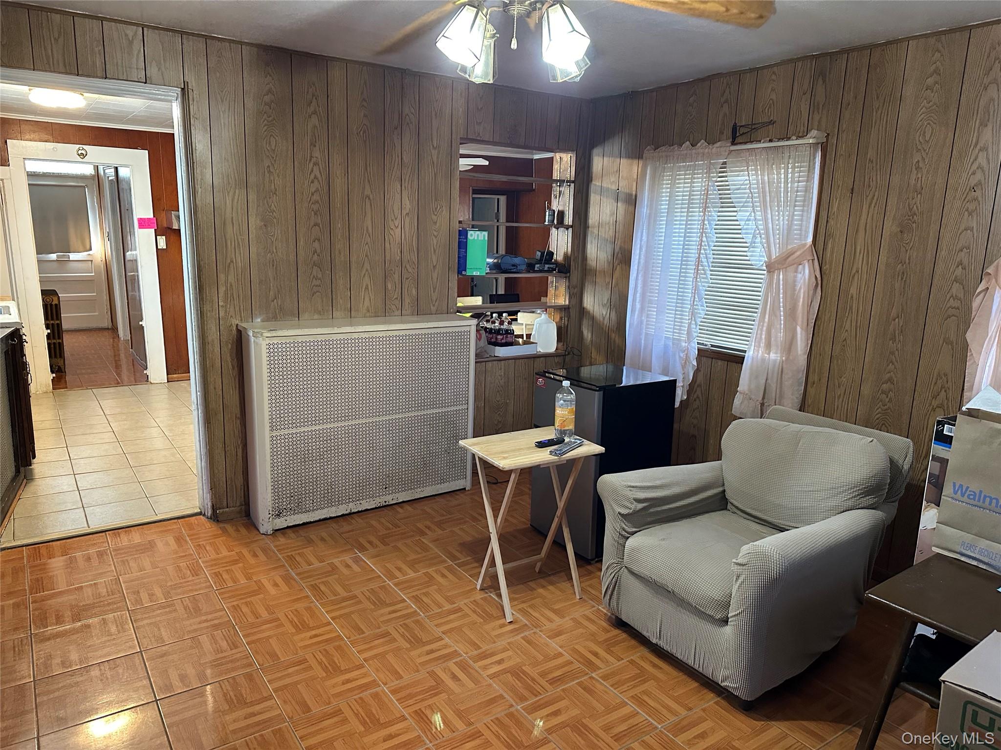 76 Church Street Beacon, NY 12508 - Photo 11 of 26 Sitting room featuring wooden walls, a ceiling fan, and radiator heating unit
